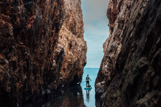 Man paddleboarding out of the narrow canyon stock photo