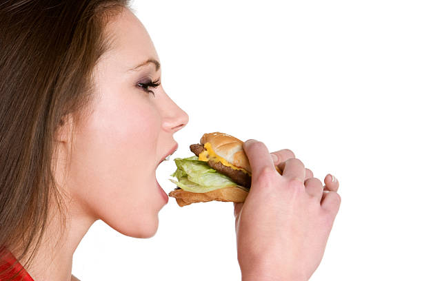istock Woman eating a hamburger against a white background 91828118