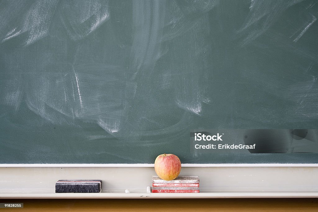 A chalk board with an apple and books underneath Used green chalkboard with erasers Chalkboard - Visual Aid Stock Photo