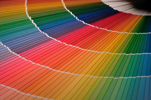 Rainbow colored paint can lids against black background.