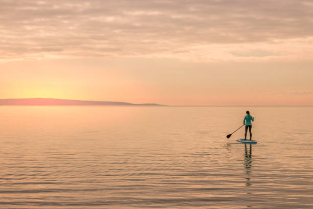 istock Girl paddling towards sunset 918289654