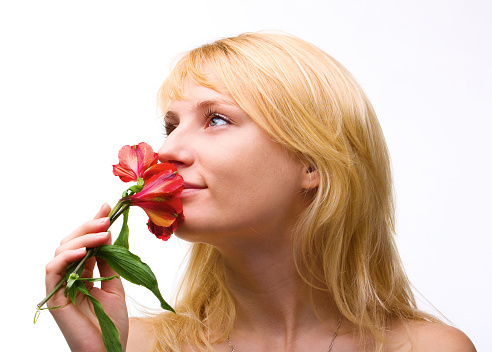 Beautiful young woman smells a red flower