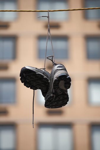 A pair of sneakers hangs high on a wire in the air\