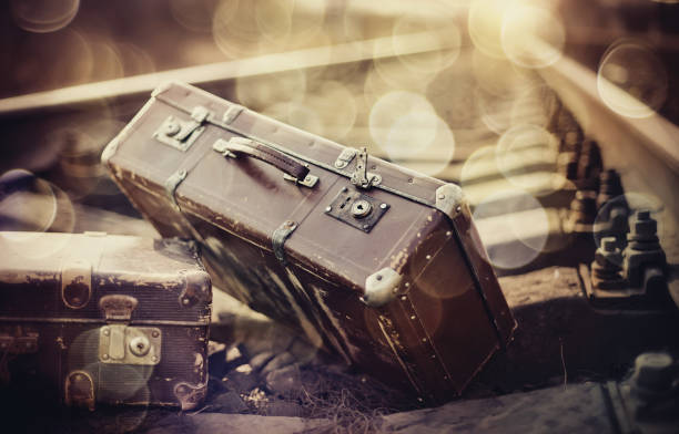 istock Two old forgotten a suitcases lie on railroad tracks 918311440