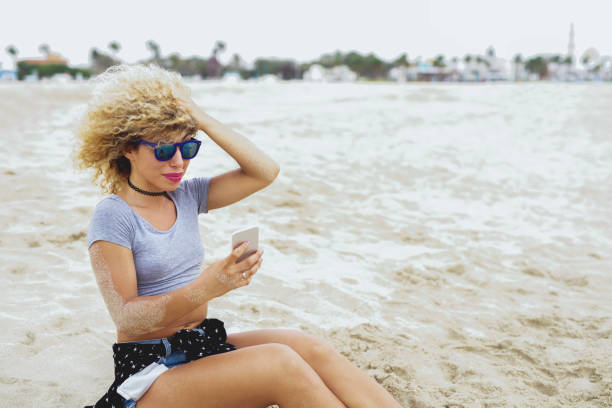 istock Female holding smart phone at beach. 918311474
