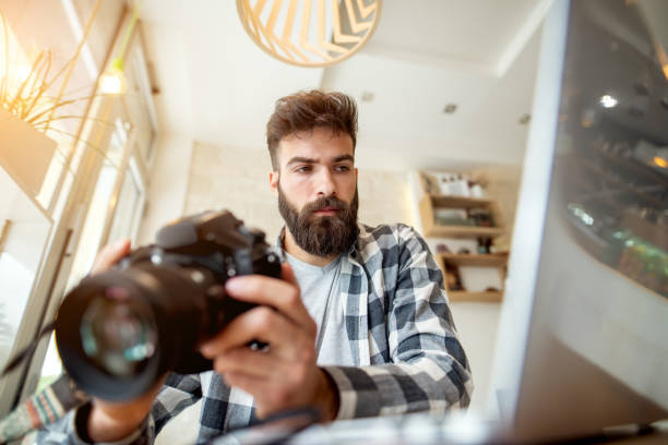 istock Young photographer adjusting settings on his camera. Preparing to retouch photos on the computer. 918318698