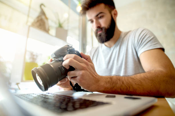 istock Young photographer adjusting settings on his camera. Preparing to retouch photos on the computer. 918319076