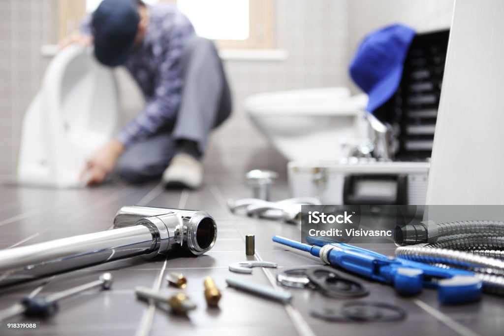plumber at work in a bathroom, plumbing repair service, assemble and install concept Plumber Stock Photo