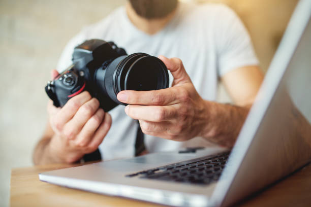 istock Young photographer adjusting settings on his camera. Preparing to retouch photos on the computer. 918322112