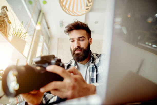 istock Photographer off loading files on laptop. Checking photos working at modern office. 918329652