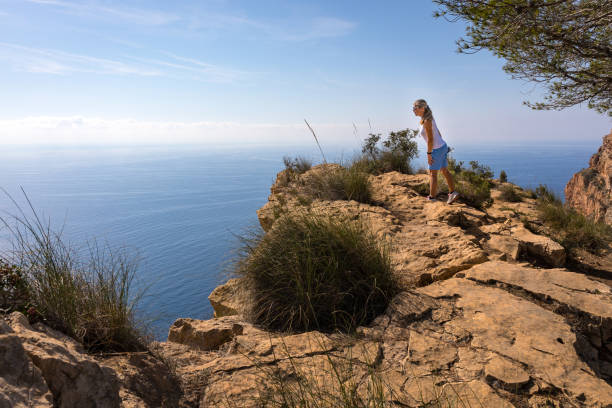 frau auf der suche über den rand einer klippe ein wenig angst - cliff at the edge of grass sea stock-fotos und bilder