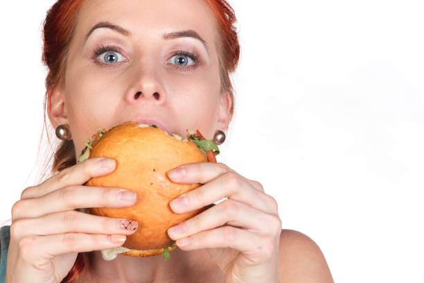 istock young woman eating  big hamburger close up 918335538
