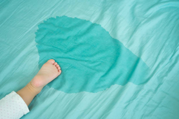 i piedi del bambino e fare pipì in un materasso. piedini e pipì in lenzuolo la mattina. concetto di sviluppo del bambino. - enuresis foto e immagini stock