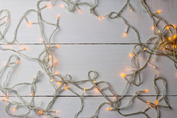 istock Christmas lights on white wooden background. top view. 918343840