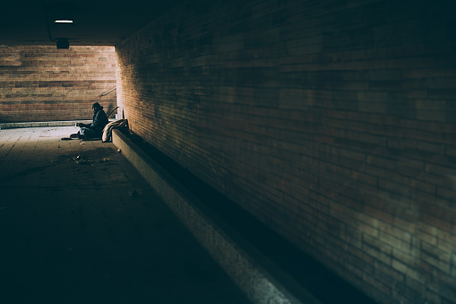 One man, young homeless sitting on the street and begging.