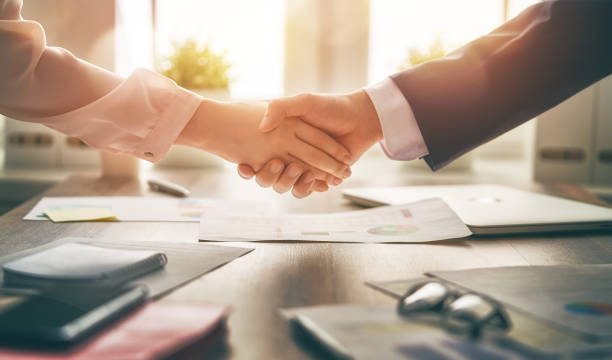 handshaking in office Man and woman are shaking hands in office. Collaborative teamwork. selling stock pictures, royalty-free photos & images
