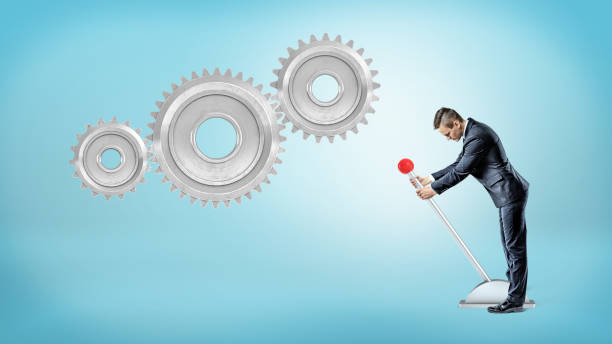 istock A small businessman pulls a large lever near three giant interlocked gears hanging on a blue background 918355960