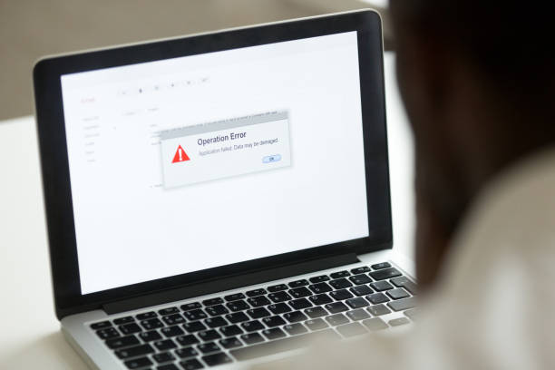 afrikanischer mann mit laptop mit anwendung fehlermeldung auf dem bildschirm - fehler problem fotos stock-fotos und bilder
