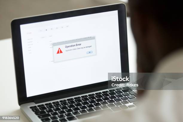 African Man Using Laptop With Application Failure Message On Screen Stock Photo - Download Image Now
