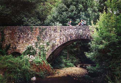 Madre e hijo sentarse en el viejo puente de viaducto sobre el río bosque photo