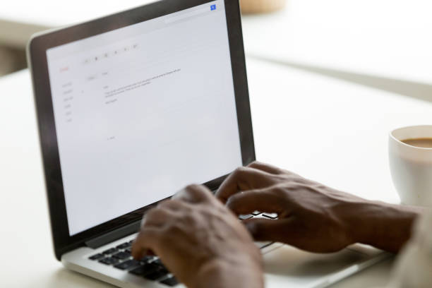 african american businessman typing e-mail on laptop using online application - correspondência imagens e fotografias de stock