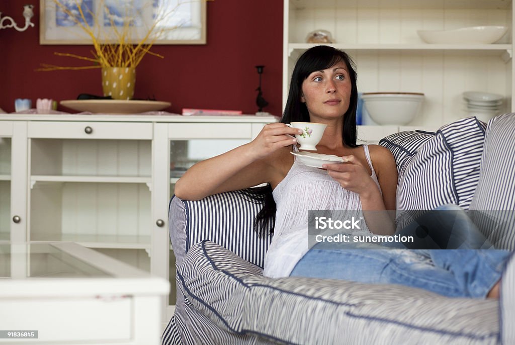 Mujer en su casa en el sofá con taza de té - Foto de stock de Acogedor libre de derechos