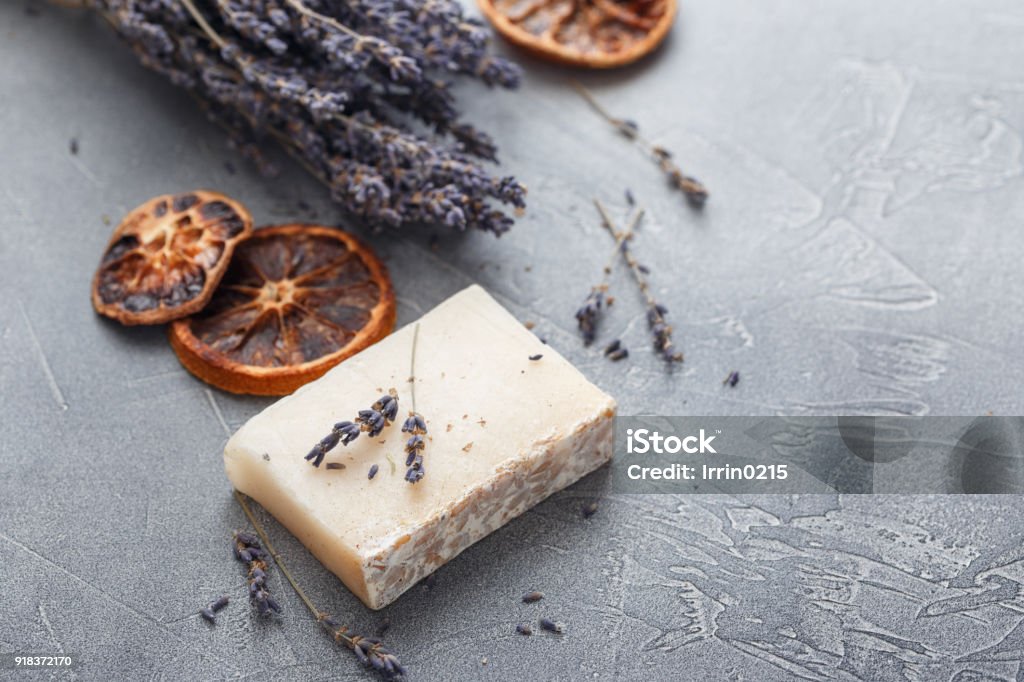 Two pieces of handmade soap Pece of handmade soap with sprigs of dry lavender and slices of dried orange on a gray background Soap Stock Photo