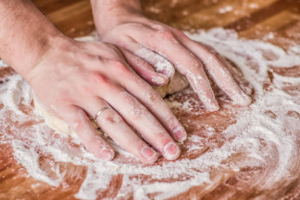 istock male hands kneading dough on wooden table 918375130