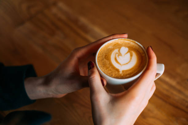 istock Lady's Hands Holding Cup With Latte Art 918375178