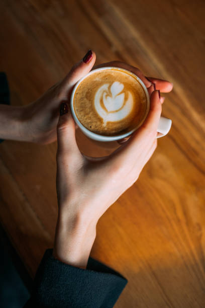istock Lady's Hands Holding Cup With Latte Art 918375186