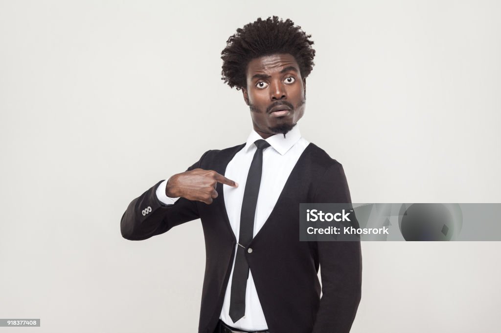 Amazement aloof afro man looking at camera. Studio shot, gray background Amazement aloof afro man looking at camera and pointing finger himself. Studio shot, gray background Pride Stock Photo