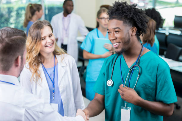 confiante jovem médico homem cumprimenta associar durante a conferência de saúde - male black medical student mature student - fotografias e filmes do acervo