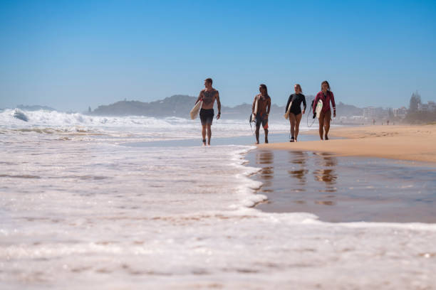 istock Friends walking along the coast with surfboards 918380840