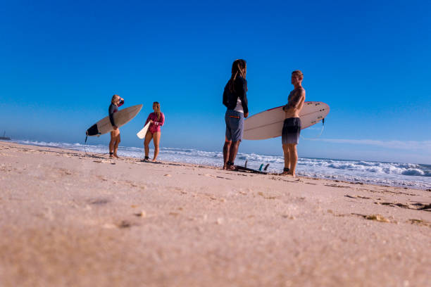 istock Friends stand on the coast and wait for high surfing waves 918380892