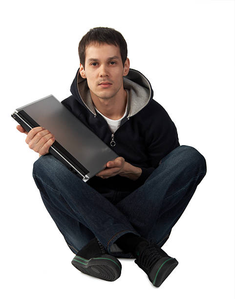 Young man with laptop sits on floor stock photo