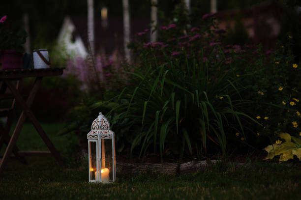 cozy evening garden scene with vintage lantern and candle holder with lawn and flowers on background cozy evening garden scene with vintage lantern and candle holder with lawn and flowers on background trowel gardening shovel gardening equipment stock pictures, royalty-free photos & images
