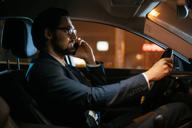 istock Businessman driving at night and using smartphone 918392754