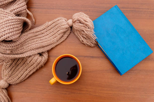 Cup of coffee, knitted scarf and book on wooden background Cup of coffee, knitted scarf and book on wooden background coffee table top stock pictures, royalty-free photos & images