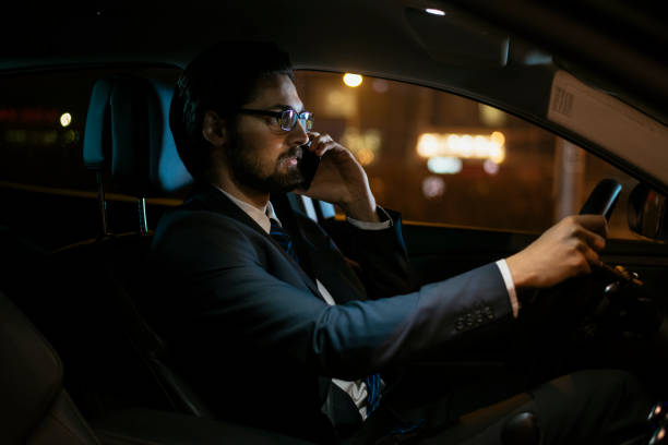 istock Businessman driving at night and using smartphone 918396422