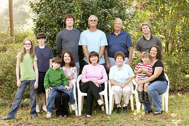 Large family portrait in the garden Large family of 12 sittiing outside during a family gathering. family reunion stock pictures, royalty-free photos & images