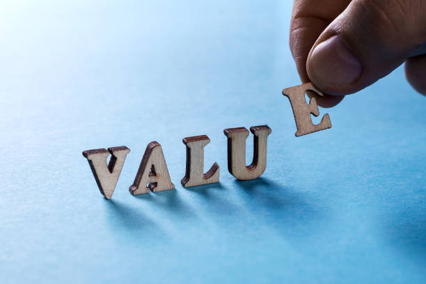istock VALUE from wooden letters on a blue background, a man's hand holds a letter E 918403600