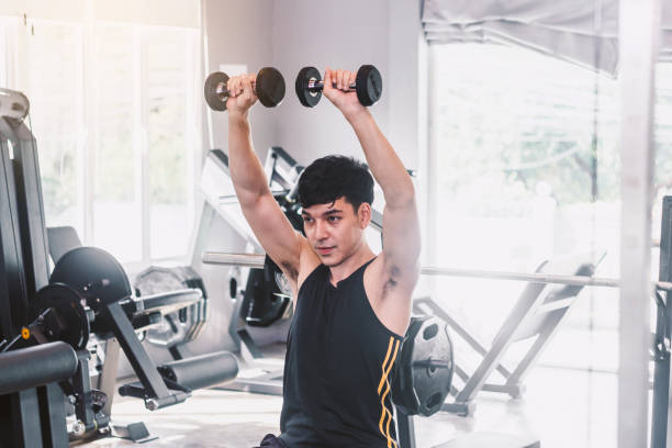 istock Fitness man doing weights exercises with dumbbell sitting at the gym 918407372