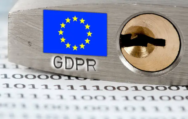 Macro photo of padlock and data on the paper with EU flag and GDPR letters imprinted on metal surface