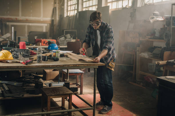 istock Male carpenter using paint brush while working on a piece of wood. 918413288