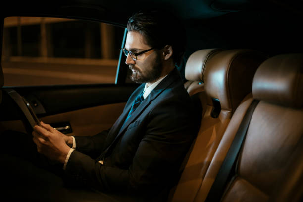 istock Businessman sitting on back seat and using tablet 918415300