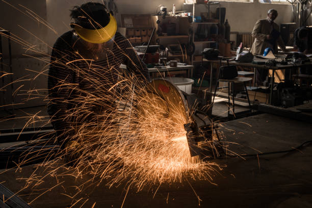 istock Manual worker working in a factory while welding an iron with electric saw. 918419184