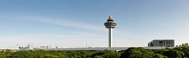 The control tower of Changi Airport in Singapore. this panoramic shows off the garden city's green trees, blue skies and cleanliness. the air traffic control tower sticks out into the sky. 