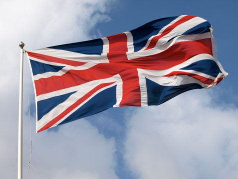 A British flag blows in the wind against the blue skies