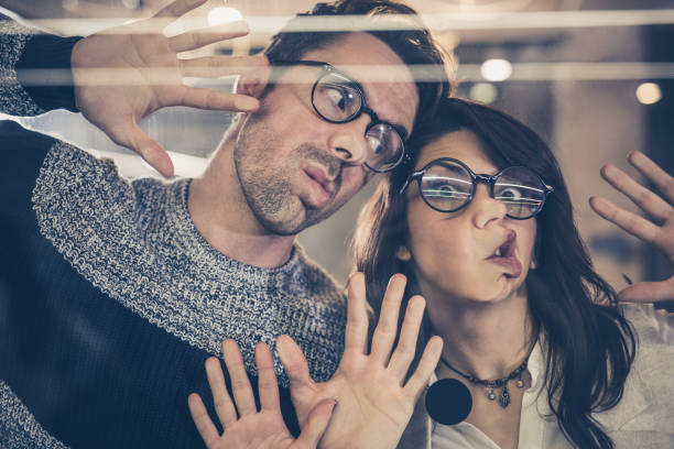 istock Young playful entrepreneurs making faces while playing on glass wall. 918430820