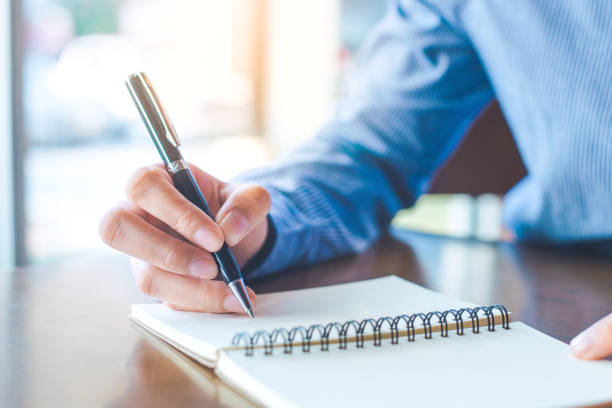 istock Business woman hand is writing on notepad with pen in office. 918436610